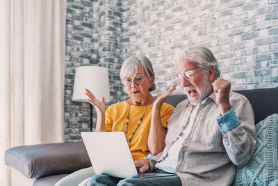Friends using laptop while sitting at home