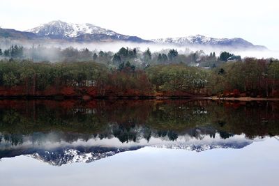 Scenic view of lake by snowcapped mountains against sky