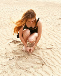 Young woman making heart shape on beach