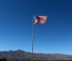 Low angle view of flag against clear blue sky