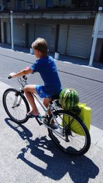 Boy riding bicycle on street during sunny day