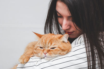 Portrait of a beautiful fashionable brunette girl with a red cat.