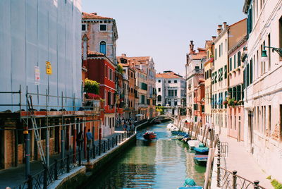 Canal in city against clear sky