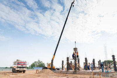 Builder contractor with theodolite transit equipment at construction site outdoors during work.