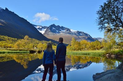 Rear view of couple standing against lake and mountains