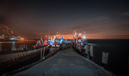 Pier at harbor against sky at night