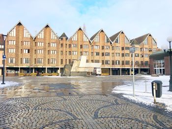 Houses by street against sky during winter