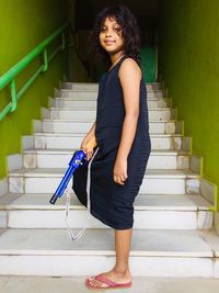 Portrait of young woman standing against wall