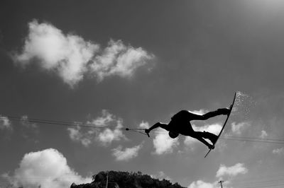 Low angle view of silhouette person wakeboarding in mid-air against sky