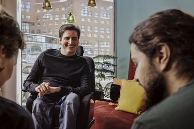 Smiling man on wheelchair talking with friends