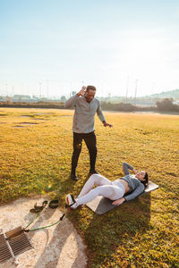 Woman exercising with instructor on land in sunny day