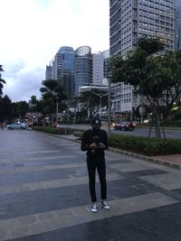 Full length rear view of man walking on street against buildings