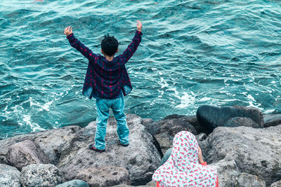 High angle view of woman and boy on rocks by sea