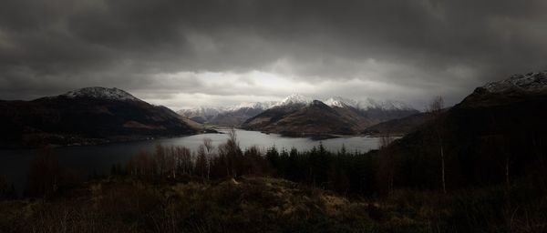 Idyllic shot of lake amidst mountains against cloudy sky