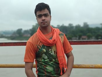 Portrait of young man standing against lake