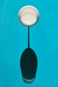 View from above of a glass of milk against blue background under natural light