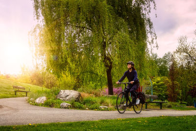 Man riding bicycle on road against trees