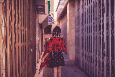Rear view of woman standing amidst alley