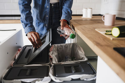 Woman recycling plastic bottles in kitchen at home