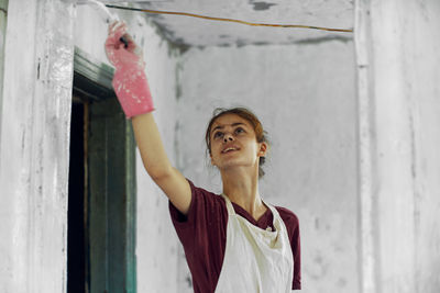 Portrait of young woman standing against wall