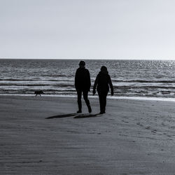 Rear view of people on beach against clear sky