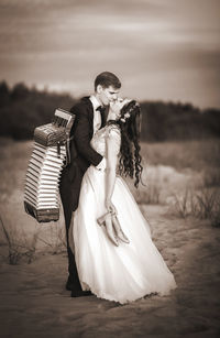 Couple kissing at beach against sky