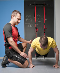 Personal trainer helping client with suspension training in gym