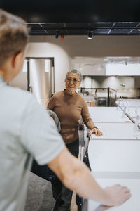 Senior woman discussing with male sales clerk by washing machines in electronics store