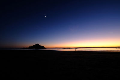 Scenic view of beach against sky at sunset