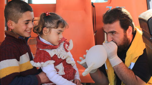 Father blowing balloon for children at home