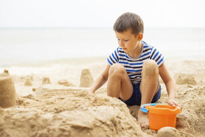 Side view of boy sitting at beach