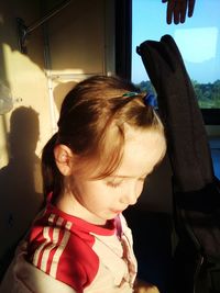 Close-up of girl standing by guitar case in train