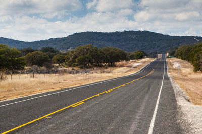 Road by mountains against sky