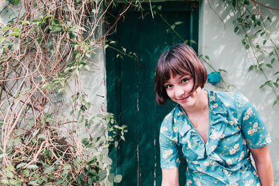 Portrait of smiling woman standing against plants