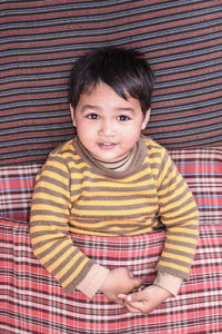 Directly above portrait of boy relaxing on bed