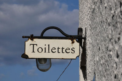 Historical toilet signpost against a blue sky