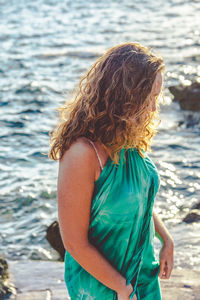 Woman wearing green dress standing by sea