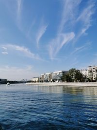 View of buildings by river against blue sky