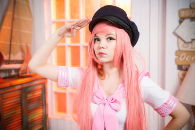 Close-up of young woman standing on pink indoors