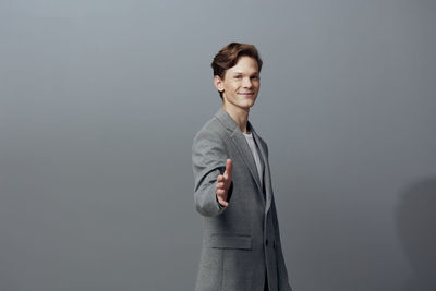 Portrait of young woman standing against gray background