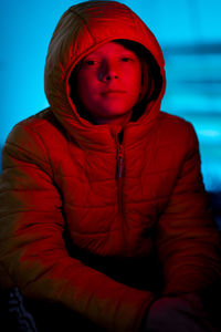 Portrait of tween covered in red light with blue light in background