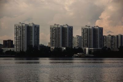 Buildings by river against sky in city
