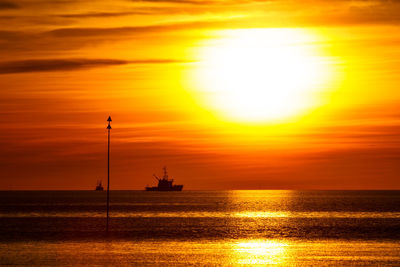 Silhouette boat sailing in sea against sky during sunset