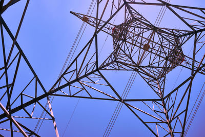 Power line metal pylon with high voltage cables bottom up view.