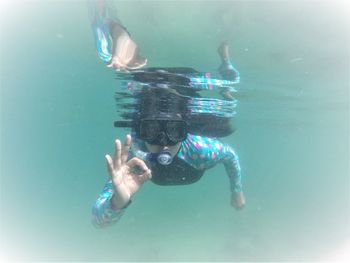 Portrait of scuba diver gesturing ok sign while swimming in sea