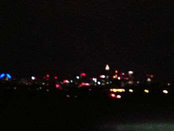 Defocused image of illuminated city against sky at night