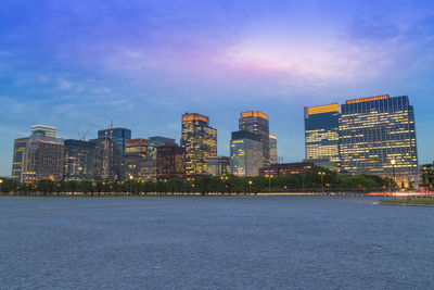 Illuminated city buildings against sky at dusk