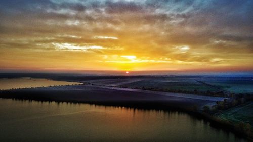 Scenic view of river against dramatic sky during sunset