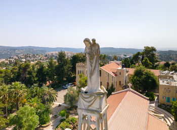 Statue against buildings in city against clear sky