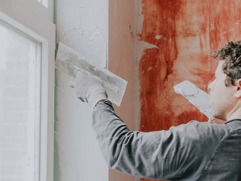 A caucasian young guy levels fresh putty with a spatula on a window opening